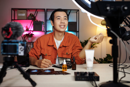 Horizontal medium selective focus portrait of handsome young Asian man recording content for video blog making review of beauty productsの写真素材