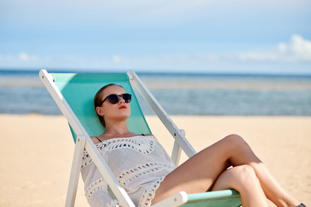 Young woman in sunglasses sunbathing on sunbed on the beachの写真素材