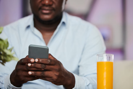 Cropped image of Black man texting friend or coworker