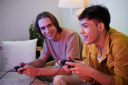 Happy excited young men playing video games at home