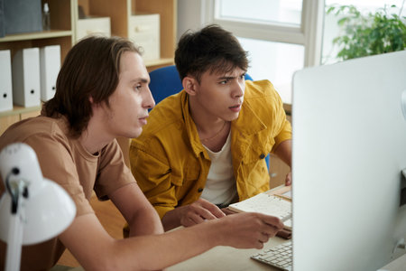 College student explaining difficult topic to friend when thay are working on project togetherの写真素材