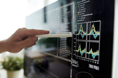 Closeup image of developer pointing at chart on computer screenの写真素材