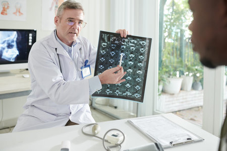 Serious doctor explaining patient why he has to care about spine health and pointing at discs MRI...