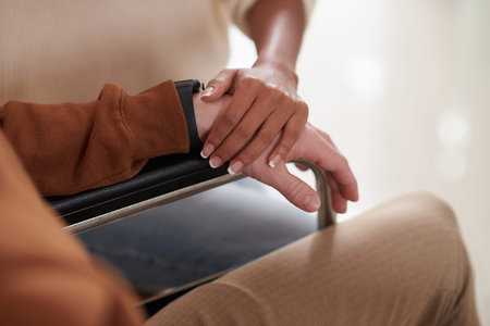 Closeup image of woman touching hand of her boyfriend sitting in wheelchair