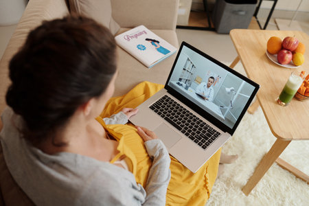 Pregnant woman video calling her gynecologyst to discuss morning sickess and medical tests resultsの写真素材