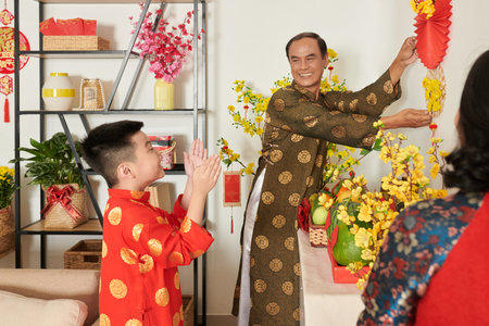 Excited little boy clapping to grandparents decorating apartment for Tet celebrationの写真素材