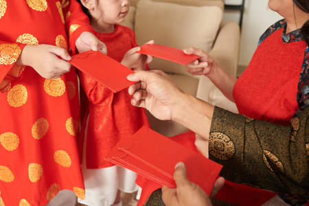 Hands of grandparents gifting lucky money envelopes to children when celebrating Spring festival at...