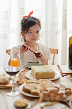 Adorable little girl eating traditional dish at Tet celebration dinnerの写真素材