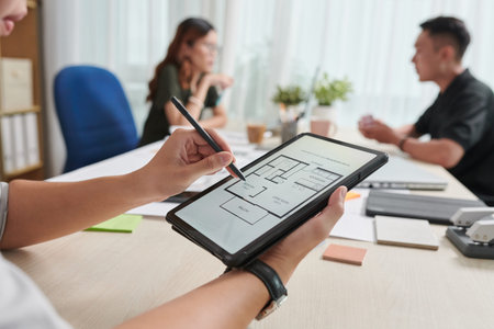 Closeup image of interior designer checking house blueprint on tablet computer