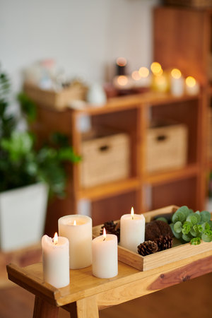 Burning candles, pine cones and flower on wooden tray in spa salonの写真素材