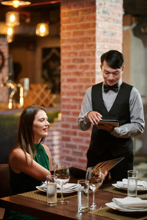 Smiling elegant woman ordering food at restaurantの写真素材