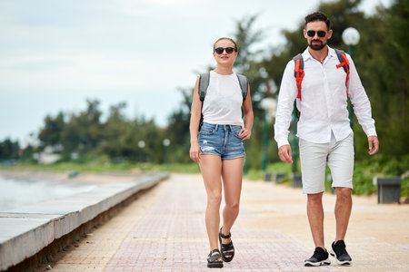 Positive couple in sunglasses walking along coastlineの写真素材
