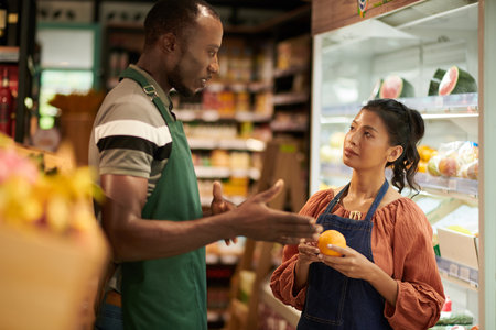 Supermarket manager explaining new employee where to put fresh fruitsの写真素材