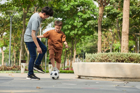 Father and son playing soccer in park on Saturday morningの写真素材