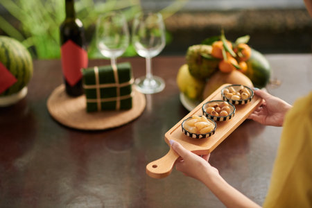 Woman bringing serving board with pickled onions and daikon to Tet dinner tableの写真素材