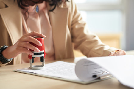 Hands of business manager applying company seal to document with annual reportの写真素材