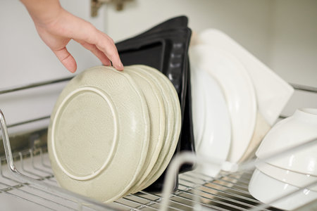 Hand of woman taking out plates to serve dinner