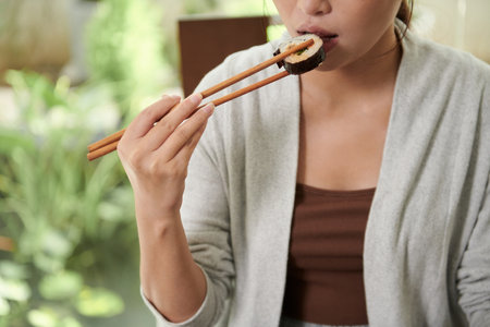 Cropped image of woman eating sushi for lunchの写真素材