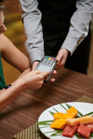 Woman paying with credit card after having dinner at restaurant