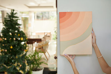 Hands of woman hanging abstract picture on wall when decorating for Chinese New Yearの写真素材