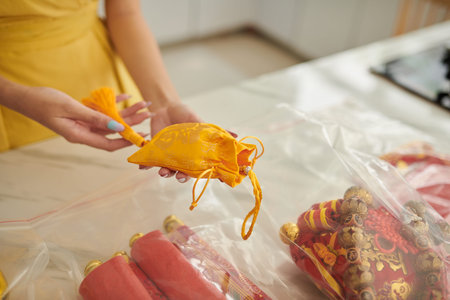 Hands of woman holding small silk yellow sack prepared for spring festivalの写真素材
