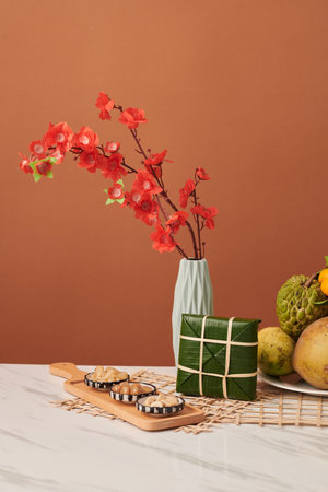 Fermented vegetables, sticky rice cake and vase with peach branches on table