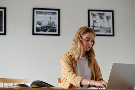 Portrait of art gallery manager working on laptop at her desk