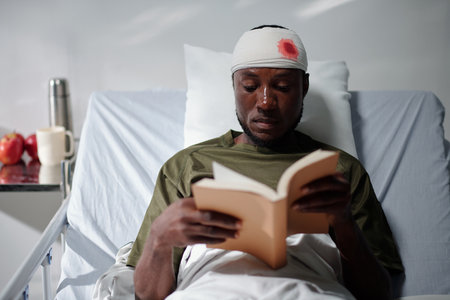 Sick military man reading good book when spending time in hospitalの写真素材