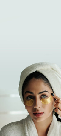 Vertical banner with young woman applying undereye moisturizing gel patchesの写真素材