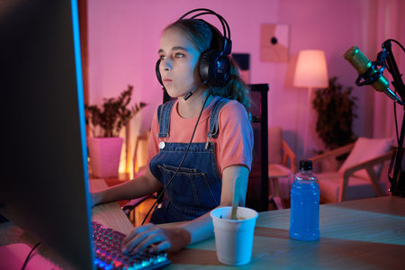 Teenage girl having ice-cream and sweet drink when playing on computer at night