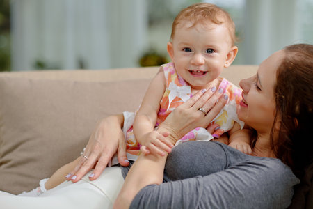 Happy mother hugging her smiling little daughter when they are spending time at homeの写真素材