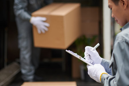 Mover signing agreement when coworker unloading truck with cardboard boxes