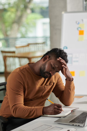 Pensive UX designer writing plans for the day before starting work on new projectの写真素材