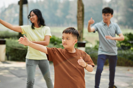 Little boy exercising in park with parents on sunny morningの写真素材