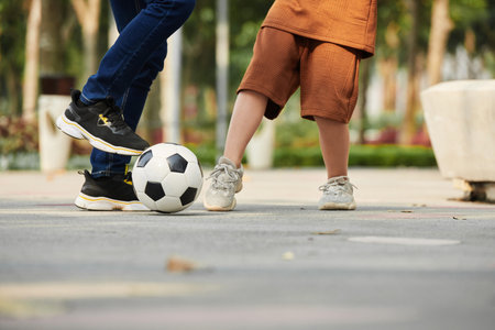 Closeup image of father playing football with preteen son
