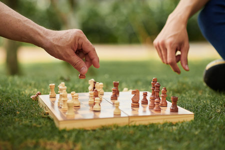 Closeup image of senior father and adult son playing chess outdoorsの写真素材