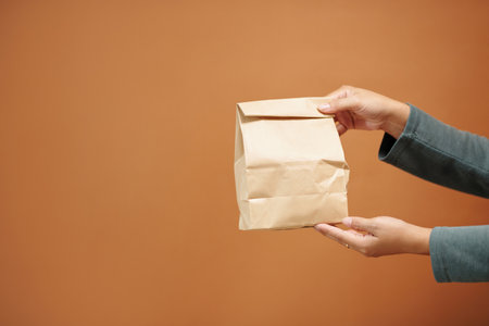 Hands of woman holding paper package with groceriesの写真素材