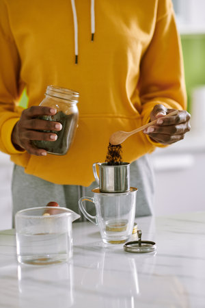 Cropped image of young woman putting ground coffee in phin filter to make Vietnamese style coffeeの写真素材