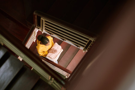 Woman with stack of towels walking up stairs, view from aboveの写真素材