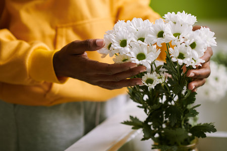 Woman enjoying beauty of fresh flowers in vase on tableの写真素材