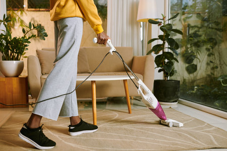 Cropped image of young woman vacuum cleaning floor in apartmentの写真素材