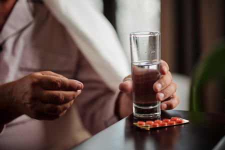 Hands of sick senior man taking pills and drinking waterの写真素材