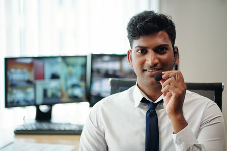 Portrait of smiling safeguard monitoring home security cameras and speaking in microphoneの写真素材