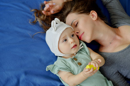 Tired young mother fell asleep next to little daughter, view from aboveの写真素材