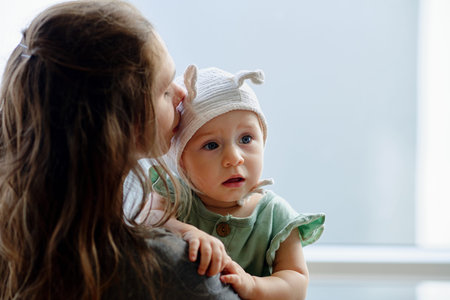 Mother kissing her adorable ccurious little girl on head