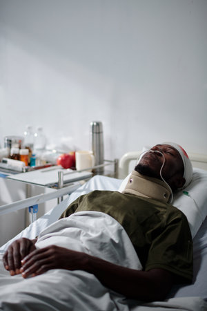 Vertical image of African American soldier lying in hospital with woundの写真素材