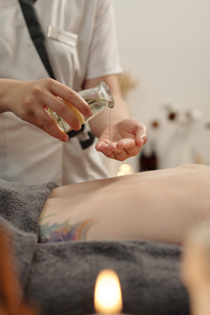 Masseuse applying oil of back of female clientの写真素材