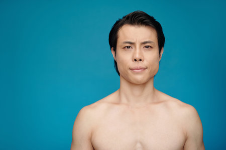 Studio portrait of shirtless fit young man looking at cameraの写真素材