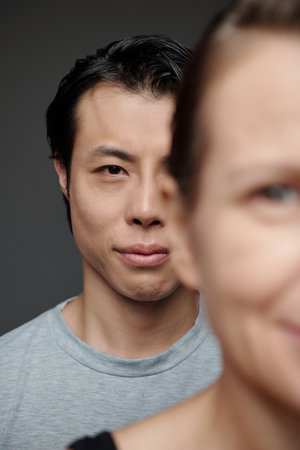 Japanese man standing behind mature woman and looking at camera, society conceptの写真素材