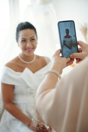 Mother photographing daughter in wedding dressの写真素材